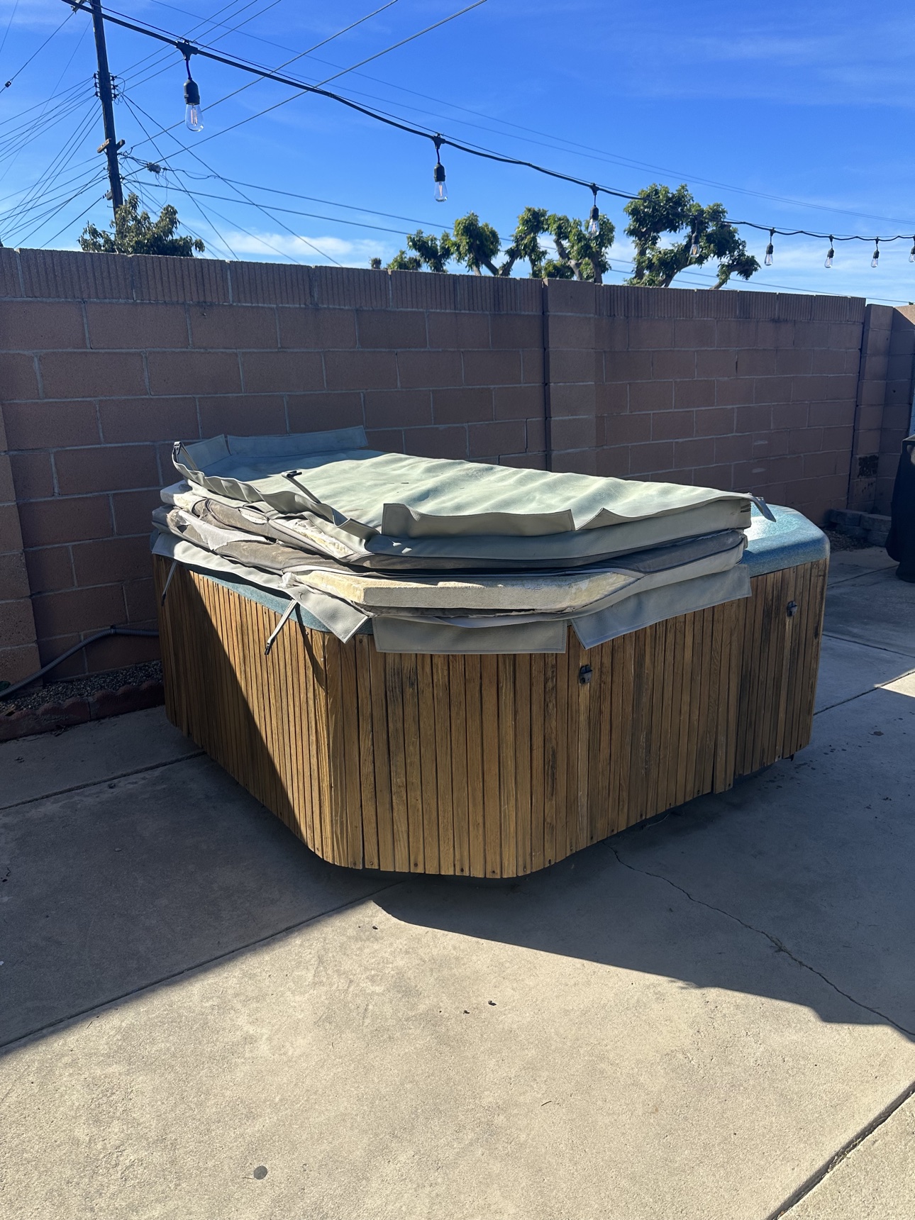 Old spa with a torn cover before Delta removed it from a Brea patio