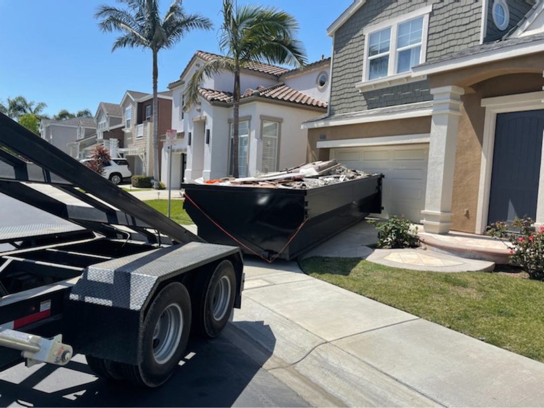 Delta roll-off dumpster loaded with construction debris in a Laguna Beach, California driveway